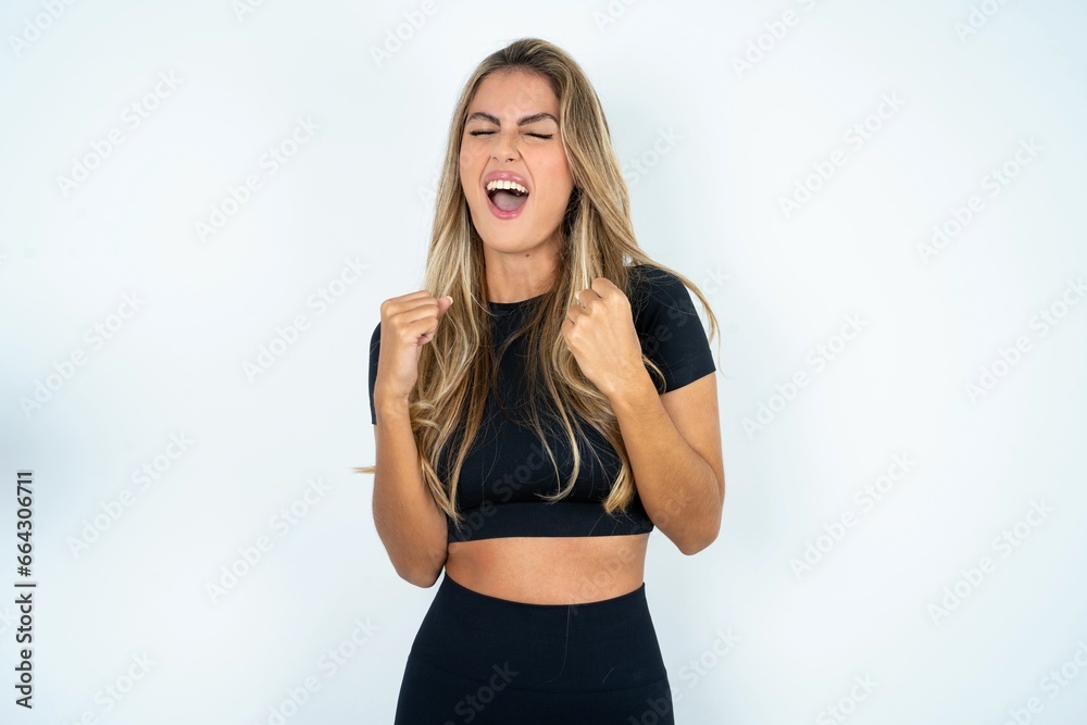 Young beautiful woman wearing sport clothes celebrating surprised and amazed for success with arms raised and eyes closed. Winner concept. Young beautiful woman wearing sport clothes celebrating surprised and amazed for success with arms raised and eyes closed. Winner concept.