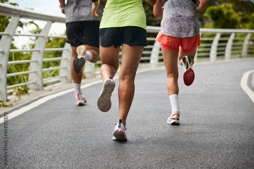 close-up shot of legs and feet of group of young asian adults people running jogging outdoors