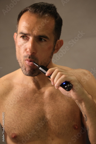 Przystojny, dojrzały mężczyzna myje zęby. A man brushes his teeth with an electric toothbrush.