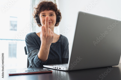 teenage girl shows middle finger while sitting in front computer