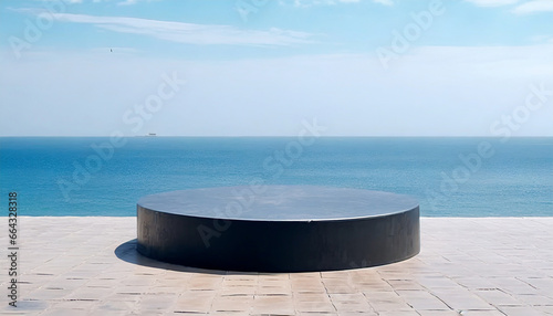 Circular black stage on the ground against a sea backdrop