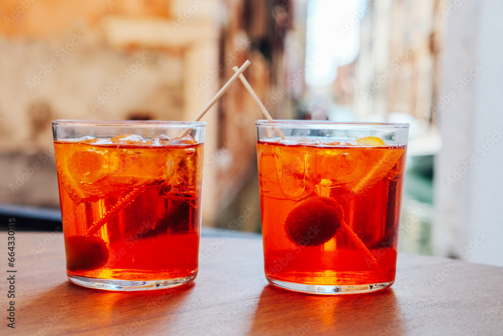 Two glasses of Aperol Spritz cocktail served near the Venetian canal. Popular italian summer aperitif drink. Venice background. Two glasses of Aperol Spritz cocktail served near the Venetian canal. Popular italian summer aperitif drink. Venice background.