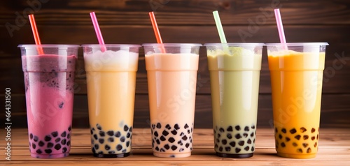 Plastic cups of different tasty bubble tea on wooden background.