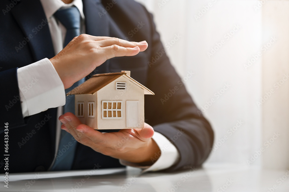 Businessman protecting house model with hands. Real estate and property Insurance concept Businessman protecting house model with hands. Real estate and property Insurance concept