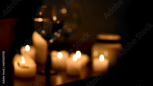 blurry background of burning candles and wine glasses in the dark. Background image for a holiday, dinner, romantic evening