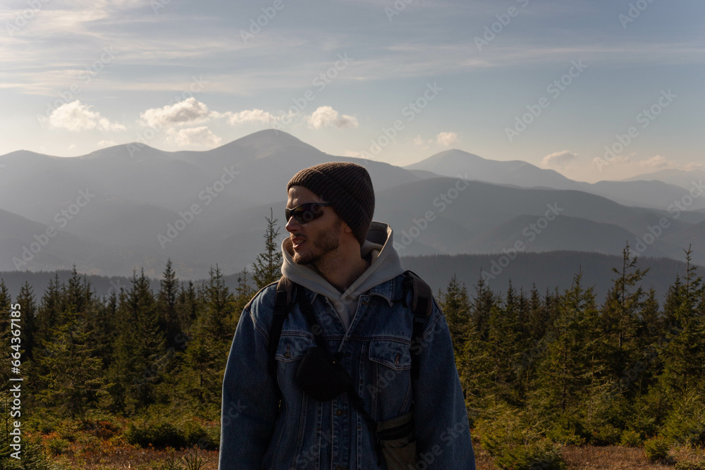 a young man stands on the background of a mountain range