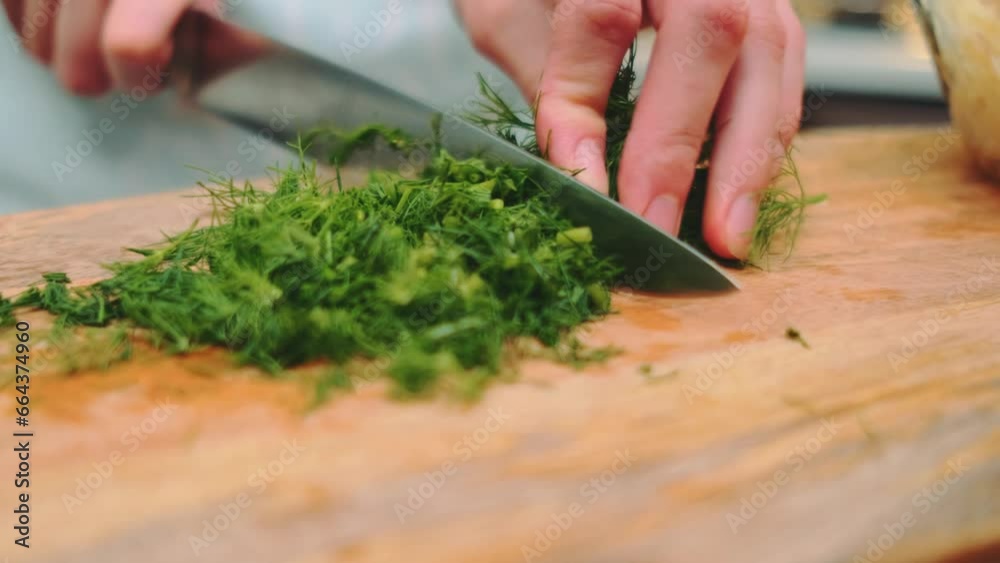 Female hands finely chop dill on a cutting board in the kitchen. Close-up of the table. Cooking in the kitchen Female hands finely chop dill on a cutting board in the kitchen. Close-up of the table. Cooking in the kitchen