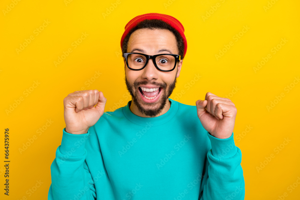 Naklejka premium Photo of impressed man wear teal sweatshirt red beanie hat scream yeah clenching fists win lottery isolated on yellow color background