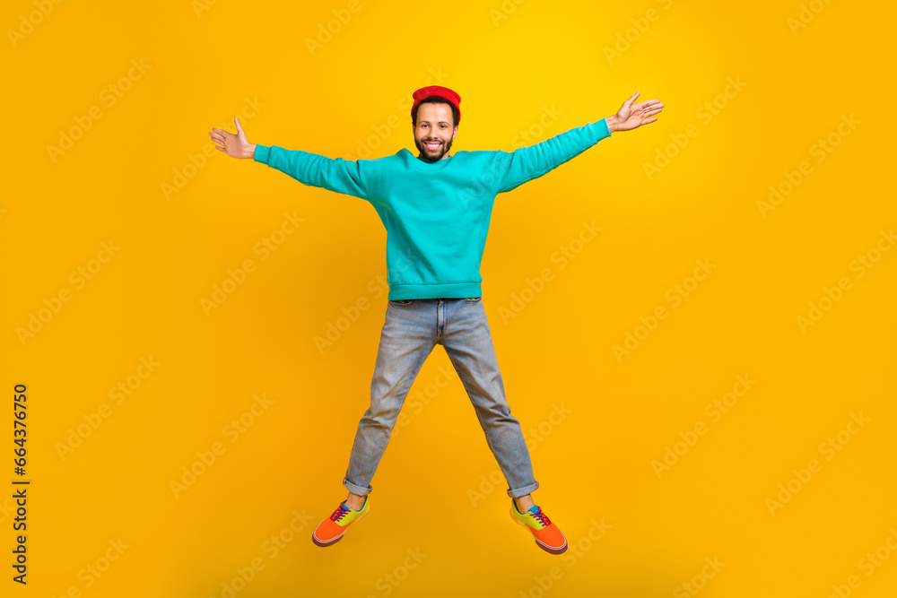 Full size photo of satisfied optimistic guy dressed red hat denim trousers flying in star pose isolated on yellow color background