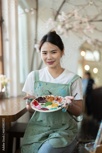 Beautiful Asian creativity woman artist smiling confident painting on canvas at art studio