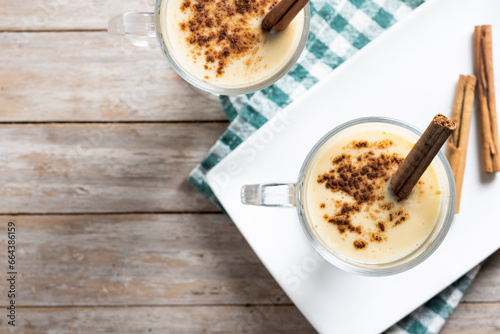 Homemade eggnog with cinnamon on wooden table. Typical Christmas dessert. Top view. Copy space