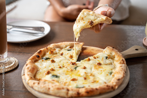 woman holding Pizza quattro fromaggi on a wooden board. Four Cheese Pizza or Quattro Formaggi Pizza topped, gorgonzola on wooden background. photo