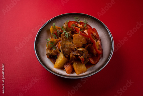 Boiled Potatoes with Meat on a Plate on a Red Background.