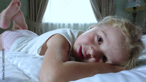 Little cute girl lying in the bed. Concept of awakening in the morning