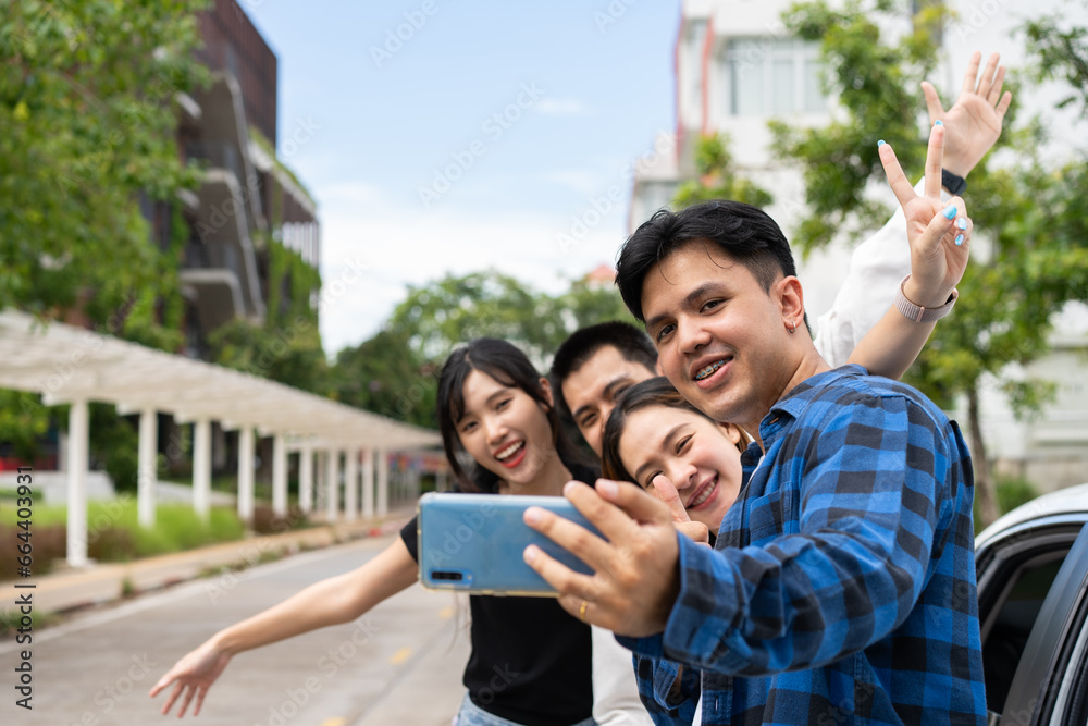 Fototapeta premium Group of happy young Asian students selfies and videos with smartphones together for vlog and social media on summer vacation. Concept of tourism and travel and road trip, friendship lifestyle.