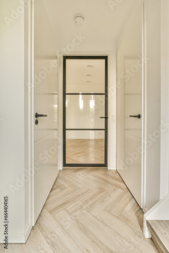 an empty room with white walls and wood flooring on either side, there is a black door in the middle © Casa imágenes