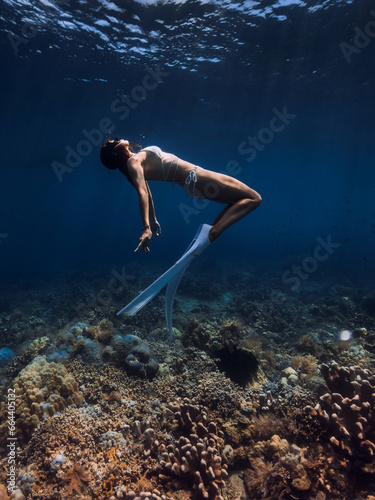 Free diver glides with fins over corals. Freediving or snorkeling in tropical ocean