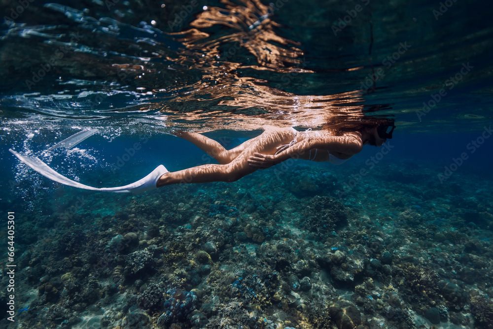 Underwater view of woman swimming near corals in transparent ocean
