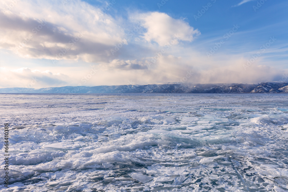 Frozen Baikal Lake. Ice hummocks and heaps of pieces of transparent ice on the Small Sea at sunset. Unusual winter landscape. Ice travel and outdoors