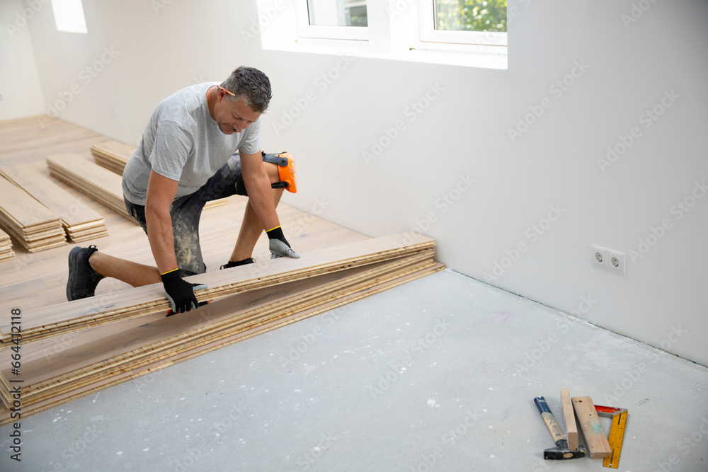 middle-aged man with gray hair glued, laying parquet floor in my loft apartment, top floor
