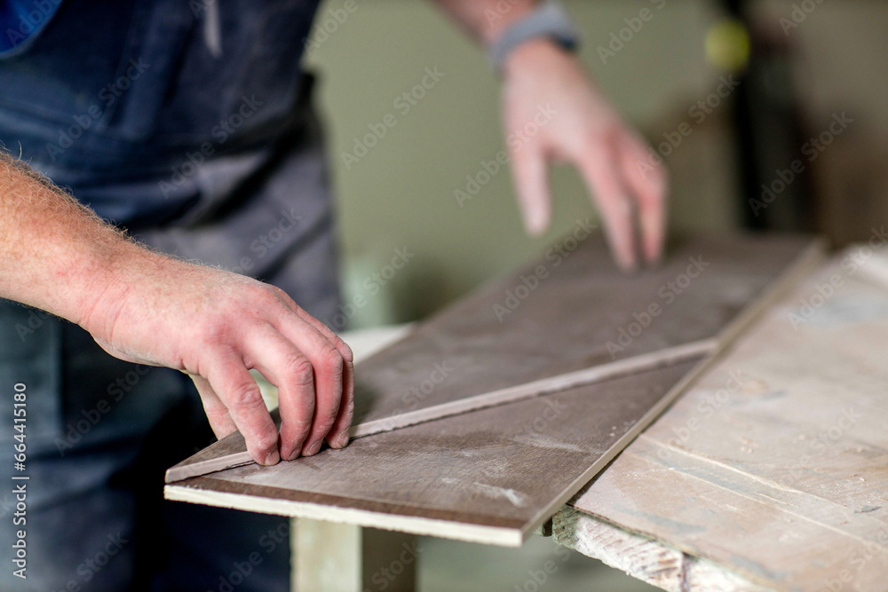 Professional tiler measuring and sticking with tape for cutting ceramic tiles for installing floor. Construction, renovation, repair apartment. Professional tiler measuring and sticking with tape for cutting ceramic tiles for installing floor. Construction, renovation, repair apartment.