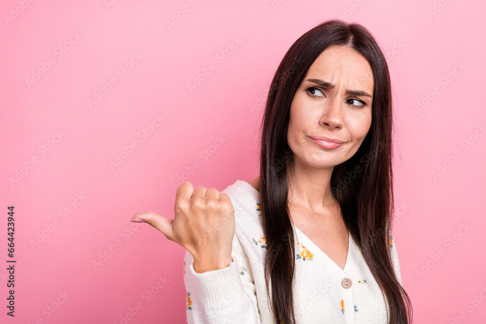 Photo of young funny strict girl direct finger empty space grimacing enjoy advertisement message ad isolated on pink color background Photo of young funny strict girl direct finger empty space grimacing enjoy advertisement message ad isolated on pink color background