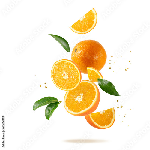 Fresh orange fruit whole and slices with leaves and drops falling flying
