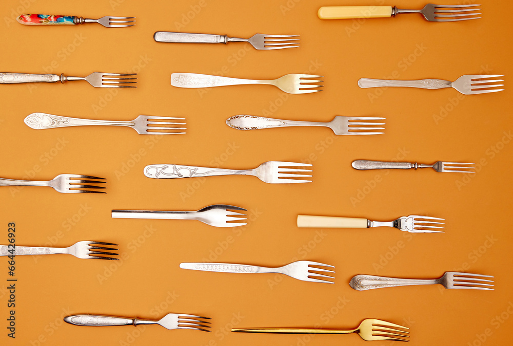 Cutlery. Top view flat lay photo of variety of antique silverware and gold forks arranged over orange studio background. Cutlery. Top view flat lay photo of variety of antique silverware and gold forks arranged over orange studio background.
