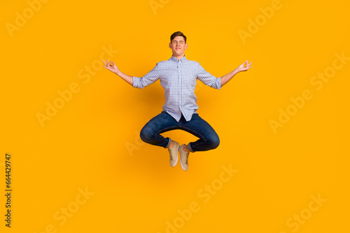 Full length photo of attractive meditating guy jumping up new asana isolated over yellow color background