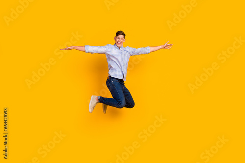 Full length body size view of attractive shopping guy jumping up show new clothes isolated yellow color background