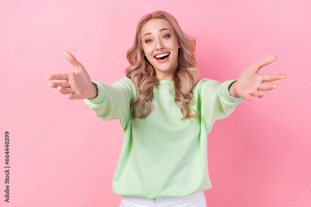 Photo of cheerful beautiful nice young lady blonde wavy curls wearing green sweatshirt cuddles you invite isolated on pink color background Photo of cheerful beautiful nice young lady blonde wavy curls wearing green sweatshirt cuddles you invite isolated on pink color background
