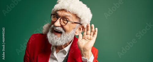 jolly man dressed as Santa with red hat with hand near ear looking at camera, winter concept, banner