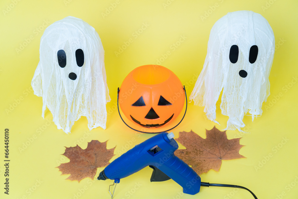 Obraz premium Halloween ghosts made from bandages, glue, water and using balloons and glasses on yellow orange background. Children's art project. DIY concept. Step by step 7. Halloween holiday concept.