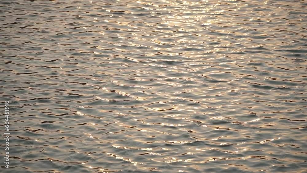 Detail and blur of the water surface which is wavy due to gusts of wind. close up and slow motion of wavy water with the reflection of yellowish sunlight in the afternoon Detail and blur of the water surface which is wavy due to gusts of wind. close up and slow motion of wavy water with the reflection of yellowish sunlight in the afternoon