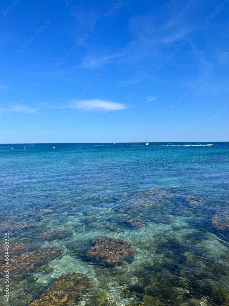 Transparent blue sea water, ocean bay, rocky coast, blue sky