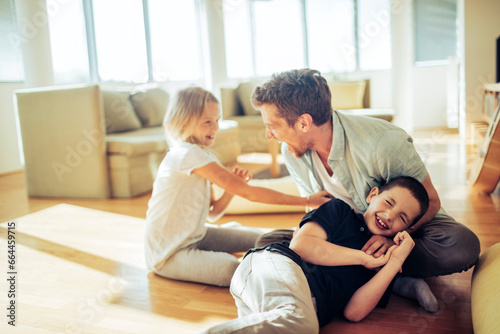 Playful young father having fun with his children in the living room