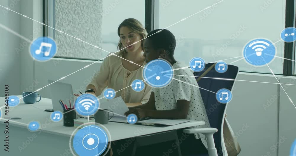 Animation of connected icons over diverse female coworkers discussing reports on laptop in office