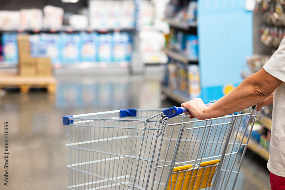 Abstract blurry photo of a supermarket with an empty shopping cart concept.