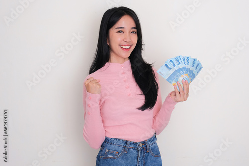 Young Asian woman showing excited expression while holding money photo