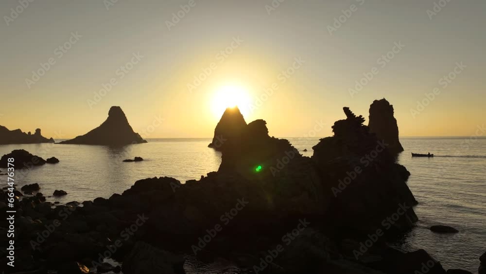 Alba sui Faraglioni dei Ciclopi, l'arcipelago di scogli difronte ad Aci Trezza, Sicilia, Italia.
Ripresa aerea controluce delle isole di Lachea con il sole giallo delle prime luci dell'alba. 