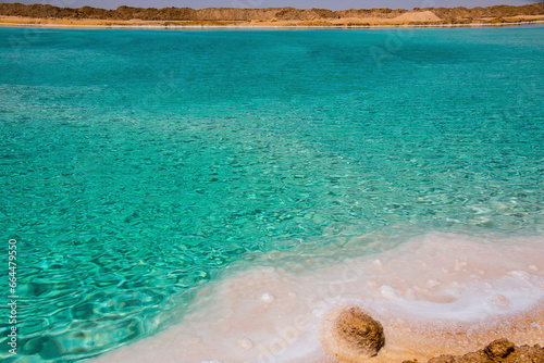 Salt lake with turquoise water and white salt on the shore near Siwa oasis, Egypt