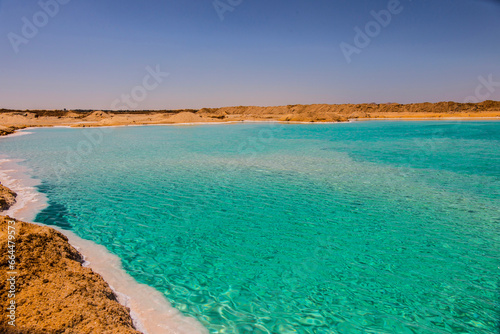 Salt lake with turquoise water and white salt on the shore near Siwa oasis, Egypt