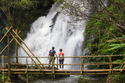 Couple seniors are walking on tropical forest trail in the outdoor recreation activities.