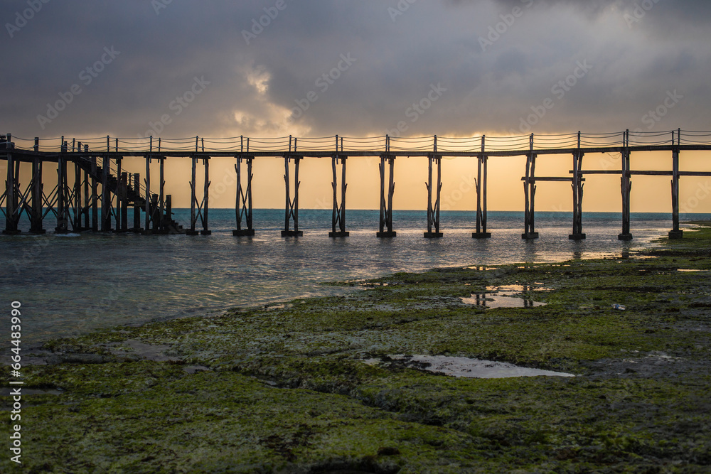 Naklejka premium Wooden walkway stretching over the sea at sunrise, Nungwi, Zanzibar, Tanzania