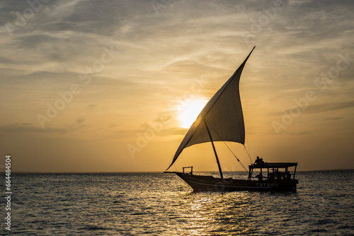 Traditional Zanzibar dhow at sunset. Sunset sky and the dhow in the sea at Zanzibar, Tanzania photo