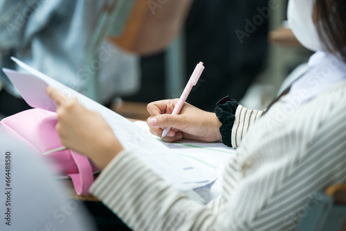 Selective focus high school or university students concentrate writing on paper answer sheet for final exam in the classroom