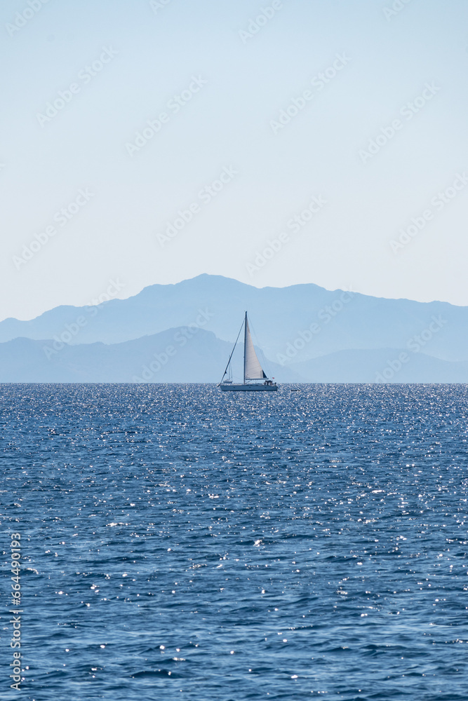 Little sailing ship traveling on the Mediterranean Sea between the coast of Greece and Turkey on a calm summer morning