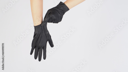  Hand is pulling black latex gloves on white background.
