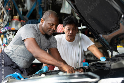 mechanics or workers checking and fixing a car in garage