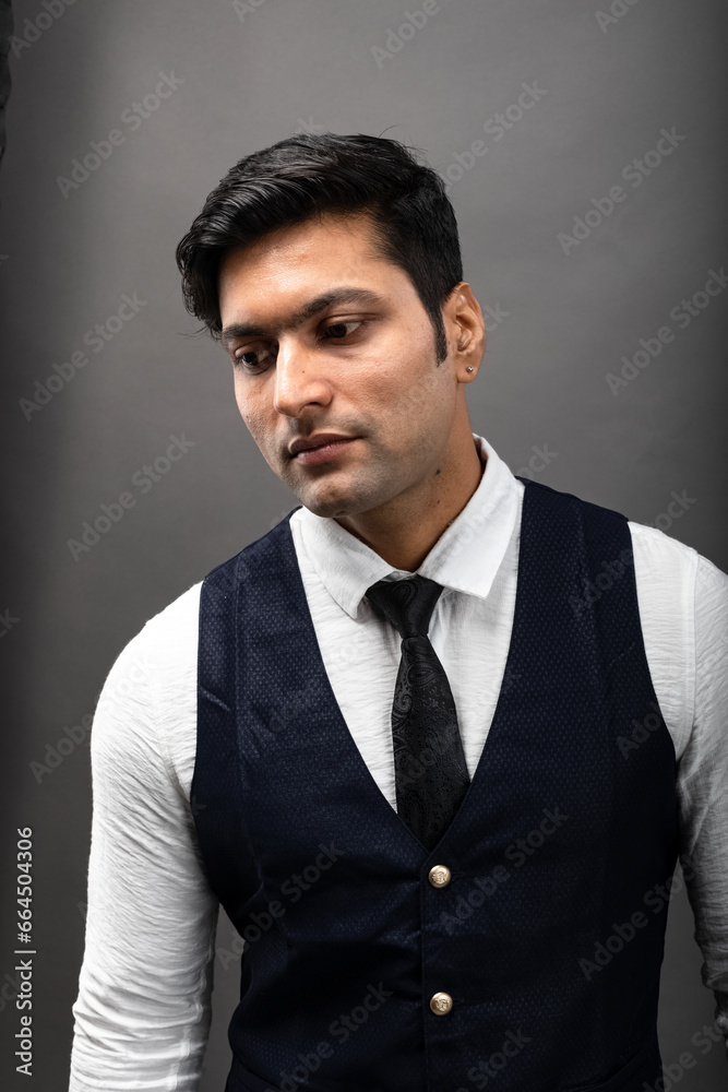 Studio shot of cheerful, young, handsome Indian business man in formal wear against grey background. Corporate male model. Fashion Portrait.